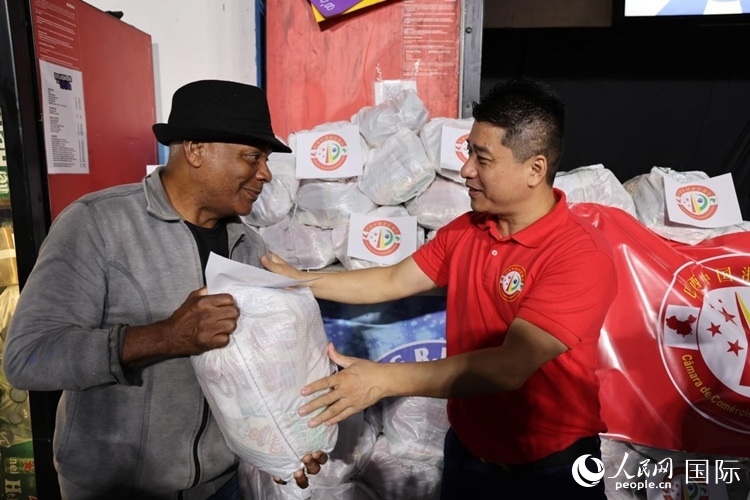 巴西中國浙江商會會長鄭俠茂向社區(qū)居民轉交捐贈物資。人民網(wǎng)記者 時元皓攝