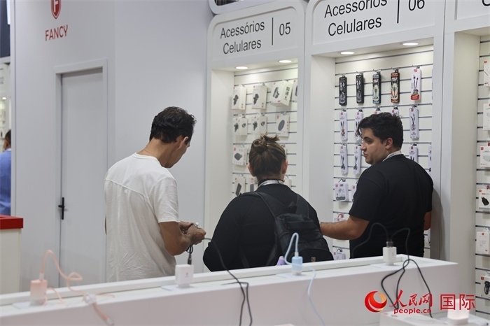 幾名參觀者在一個(gè)展臺(tái)前了解手機(jī)配件。（人民網(wǎng)記者 時(shí)元皓攝）