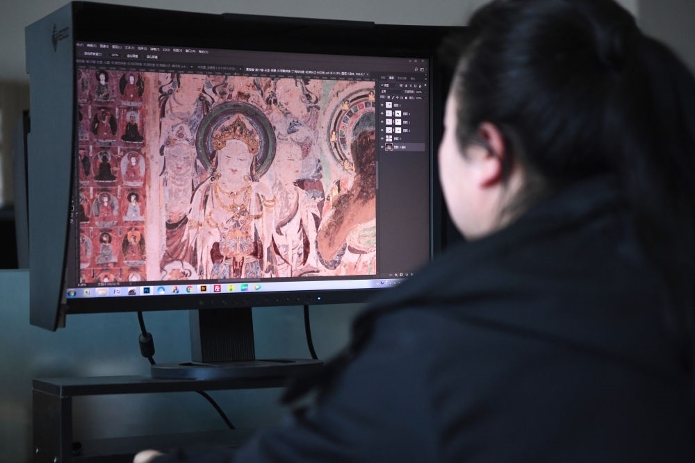 敦煌研究院文物數(shù)字化保護(hù)團(tuán)隊圖像處理人員年海麗在拼接壁畫圖像（2023年4月25日攝）。數(shù)字化探索為莫高窟的保護(hù)與傳承開辟了全新路徑，數(shù)字技術(shù)讓敦煌文物走出洞窟，跨出國門，走向“永久保存、永續(xù)利用”。新華社記者 陳斌 攝