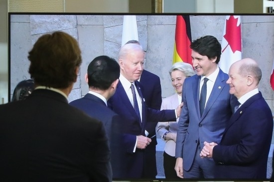 2022年3月24日，在比利時(shí)布魯塞爾的北約總部，一名男子觀看屏幕上美國總統(tǒng)拜登（右四）、歐盟委員會(huì)主席馮德萊恩（右三）、加拿大總理特魯多（右二）、德國總理朔爾茨（右一）出席七國集團(tuán)峰會(huì)合影儀式的畫面。新華社記者鄭煥松攝