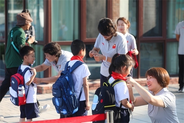 8月30日，雄安史家胡同小學(xué)學(xué)生體驗學(xué)校生活。老師為學(xué)生佩戴?；?。