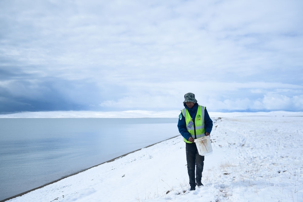 2021年10月20日，在青海省果洛藏族自治州瑪多縣扎陵湖鄉(xiāng)勒那村，三江源國(guó)家公園黃河源園區(qū)生態(tài)管護(hù)員在扎陵湖邊撿拾垃圾。新華社記者 張龍 攝