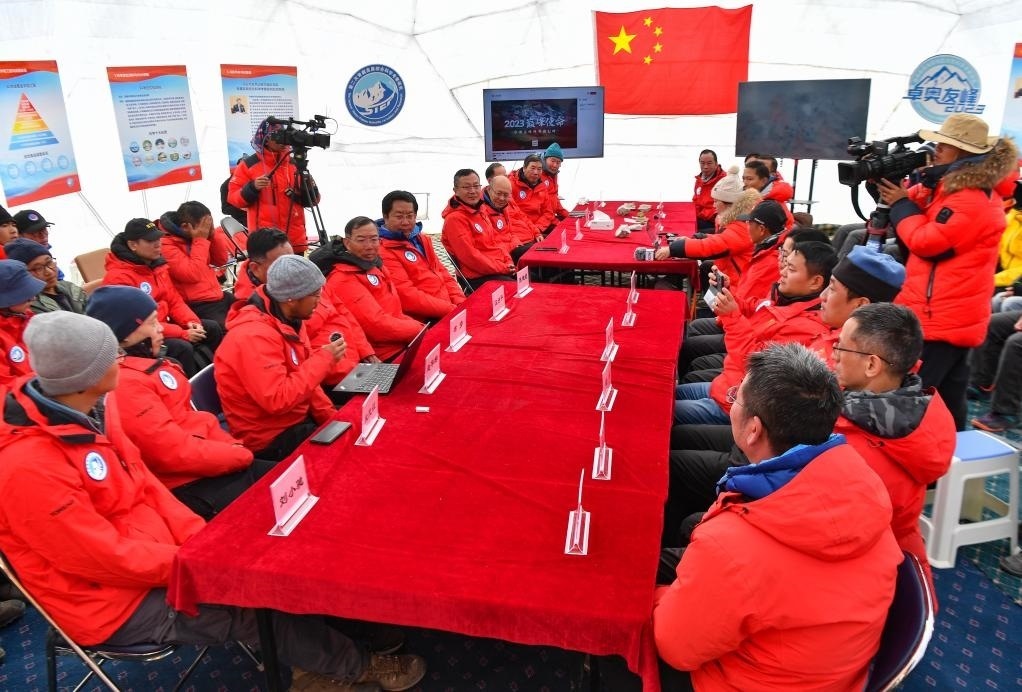 海拔4950米的卓奧友峰科考大本營，科考隊員趙華標(biāo)（手拿麥克風(fēng)看電腦者）在宣讀剛剛接收到的頂峰氣象觀測數(shù)據(jù)，這標(biāo)志著峰頂自動氣象站架設(shè)成功，成功傳回觀測數(shù)據(jù)（10月1日攝）。新華社記者晉美多吉 攝