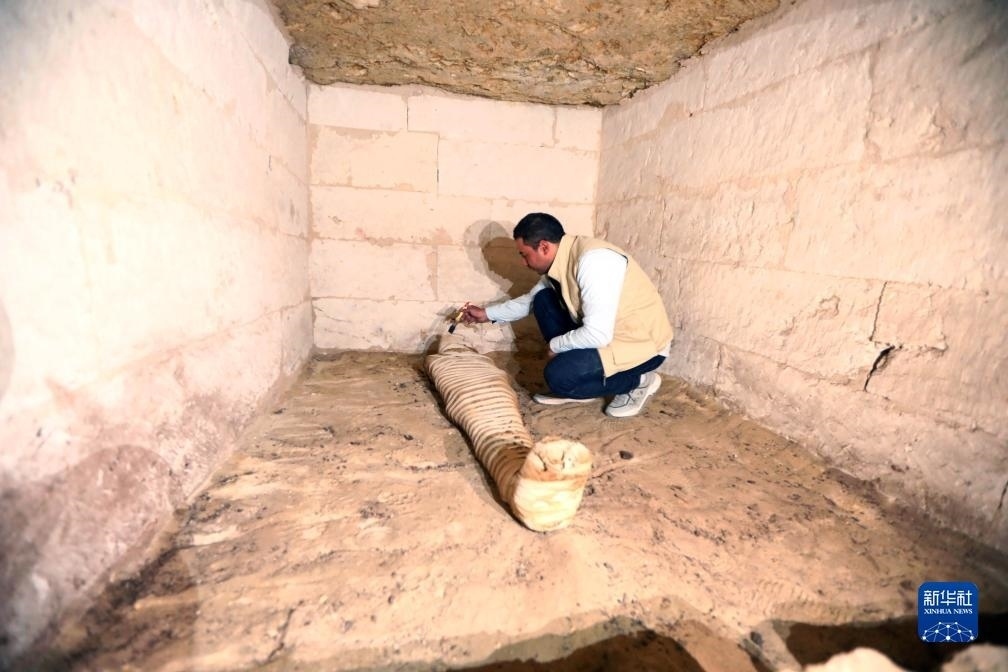 10月15日，在埃及明亞省考古現(xiàn)場，考古人員清理一座石鑿墓中的木乃伊。新華社發(fā)（艾哈邁德·戈馬攝）