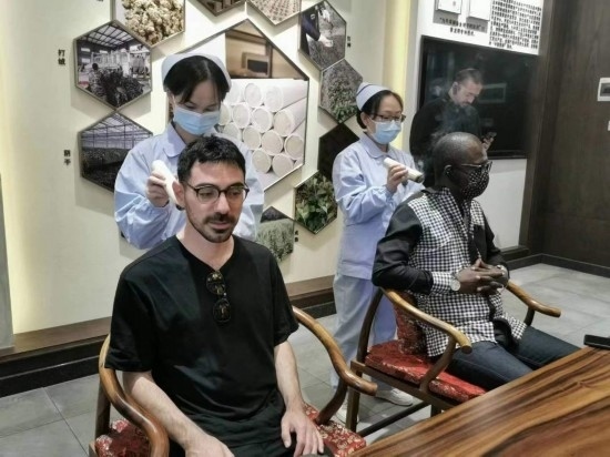 2023“一帶一路”媒體合作論壇聯(lián)合采訪團團員在九牛草展示館體驗艾灸。（本報記者 黃超攝）