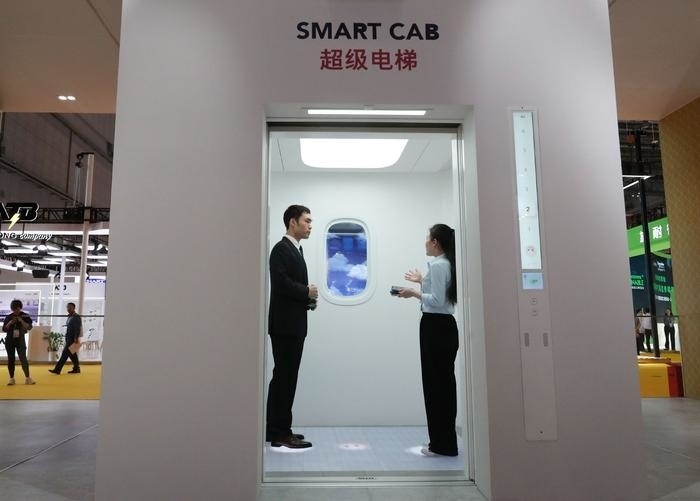 11月5日，工作人員（右）在第六屆進博會上向參觀者介紹奧的斯公司全新推出的超級電梯。