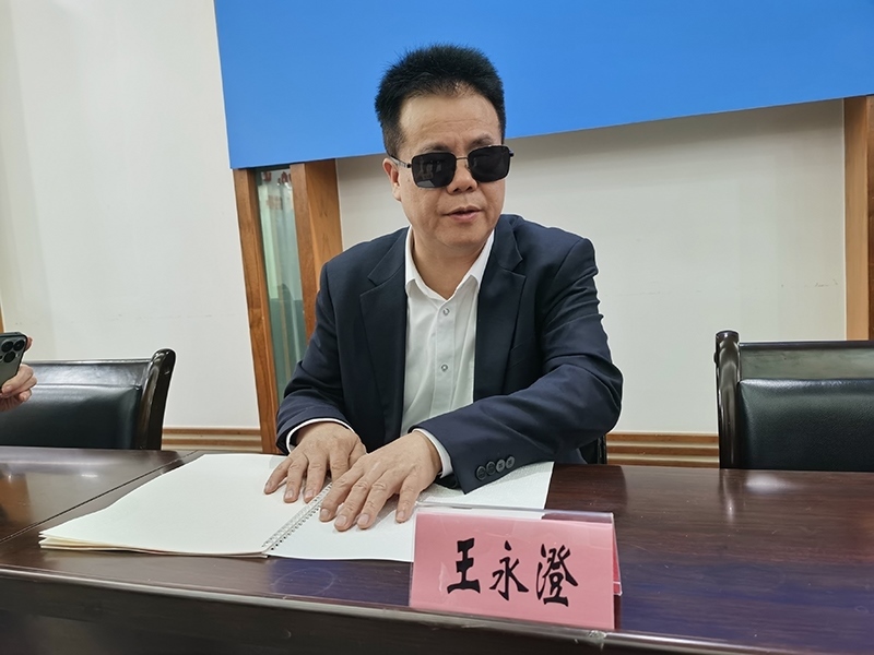 全國人大代表王永澄正在閱讀盲文版代表建議答復(fù)。本報記者 張 璁攝