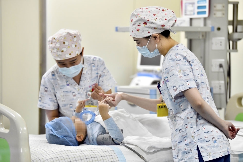 在山東省棗莊市婦幼保健院兒童ICU病房，醫(yī)護(hù)人員為完成靶向治療藥物諾西那生鈉的4歲脊髓性肌萎縮癥患兒加油鼓勁（2022年1月1日攝）。諾西那生鈉注射液是我國首個獲批治療脊髓性肌萎縮癥的進(jìn)口藥物，2019年進(jìn)入中國市場時，每針價格近70萬元。在2021年國家醫(yī)保目錄藥品談判中，以3.3萬元每針的價格進(jìn)入新版醫(yī)保藥品目錄。新華社記者 郭緒雷 攝