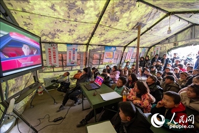 12月22日，在積石山縣大河家鎮(zhèn)大河村安置點(diǎn)，陸軍76集團(tuán)軍某旅搭建的“臨時(shí)學(xué)?！眱?nèi)，小朋友正在看動(dòng)畫片。人民網(wǎng)記者 翁奇羽攝