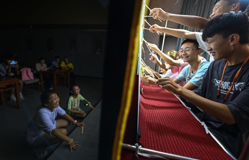 2023年8月8日，進(jìn)行暑期研學(xué)的學(xué)生在位于陜西省西安市的中國秦腔藝術(shù)博物館體驗皮影戲演出。新華社記者 鄒競一 攝