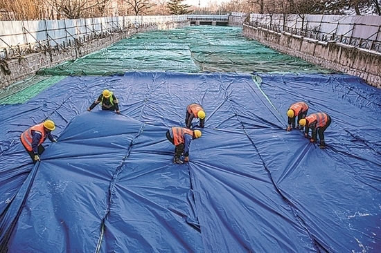 1月3日，房山區(qū)東風(fēng)街道，工人正在修復(fù)的河道內(nèi)給混凝土鋪設(shè)保溫布。