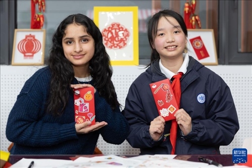 1月28日，美國馬斯卡廷中學學生（左）和復旦大學第二附屬學校學生展示互相送出的寫有寄語祝福的紅包。 新華社記者 王翔 攝