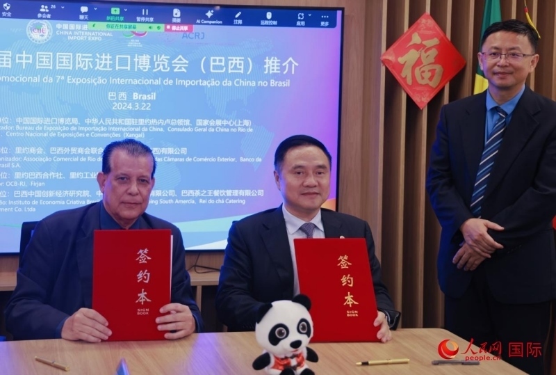 巴西外貿(mào)商會聯(lián)合會會長阿代爾·羅伯托（左）與中國國際進(jìn)口博覽局副局長吳政平（中）現(xiàn)場簽訂協(xié)議。人民網(wǎng)記者 宋亦然攝