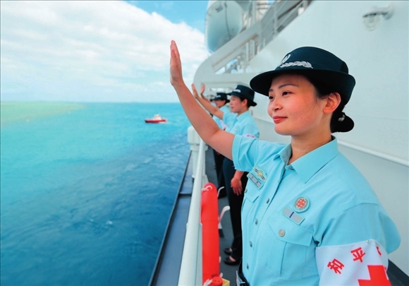 中國(guó)海軍“和平方舟”號(hào)醫(yī)院船結(jié)束訪問湯加時(shí)，任務(wù)官兵中的文職人員向歡送人群揮手告別（2023年8月4日攝）。徐巍攝/本刊