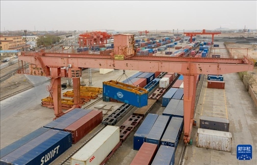 4月21日，二連浩特鐵路口岸龍門吊吊裝中歐班列集裝箱（無人機照片）。 新華社發(fā)（張海峰攝）