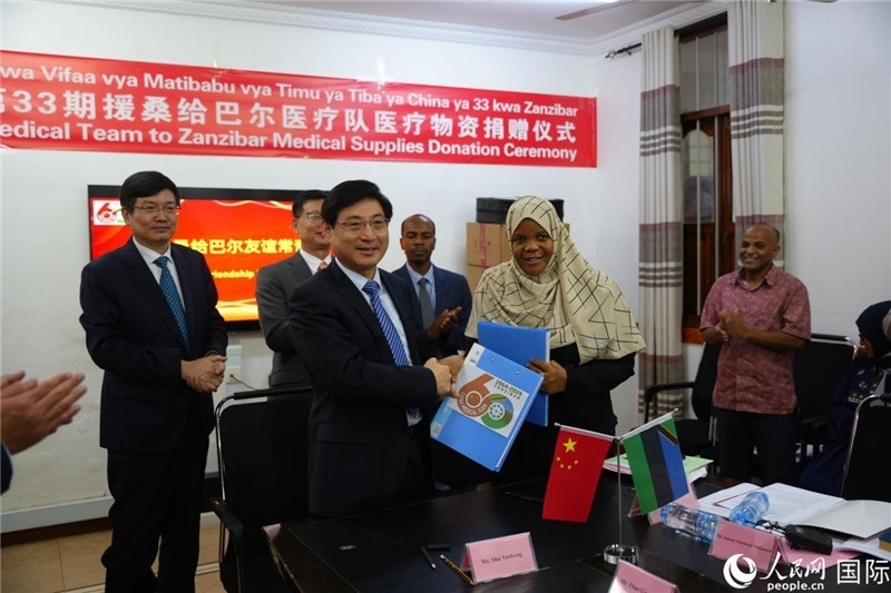 江蘇省蘇北人民醫(yī)院黨委書記束余聲與桑衛(wèi)生部首席秘書哈比巴交換捐贈書。中國援桑醫(yī)療隊供圖