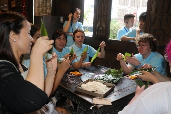 6月9日，美國青年代表在重慶永川松溉古鎮(zhèn)體驗包粽子。新華社記者 周思宇 攝