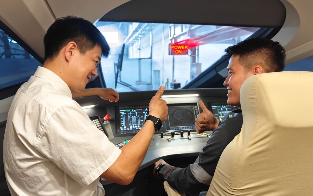 2023年8月25日，在印度尼西亞萬隆的雅萬高鐵德卡魯爾動車所內(nèi)，中國師傅穆振（左）向印尼火車司機塞蒂亞萬講解動車組出庫前的上電作業(yè)。新華社記者 徐欽 攝