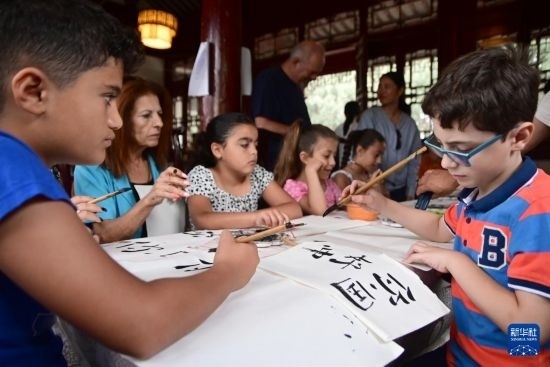 7月4日，在馬耳他桑塔露琪亞市的中國古典園林“靜園”，人們體驗(yàn)中國書法。新華社發(fā)（喬納森·博格 攝）