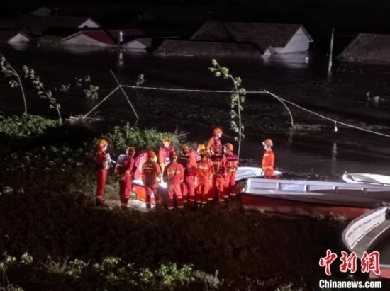  7月6日凌晨3時，在湖南岳陽華容縣團洲垸洞庭湖一線堤防，救援人員剛剛完成一次救援任務，遠處是被淹的民房。中新社記者 白祖偕 攝