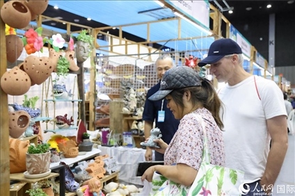 游客在蘭納博覽會特色展位上選購工藝品。人民網(wǎng)記者楊一攝