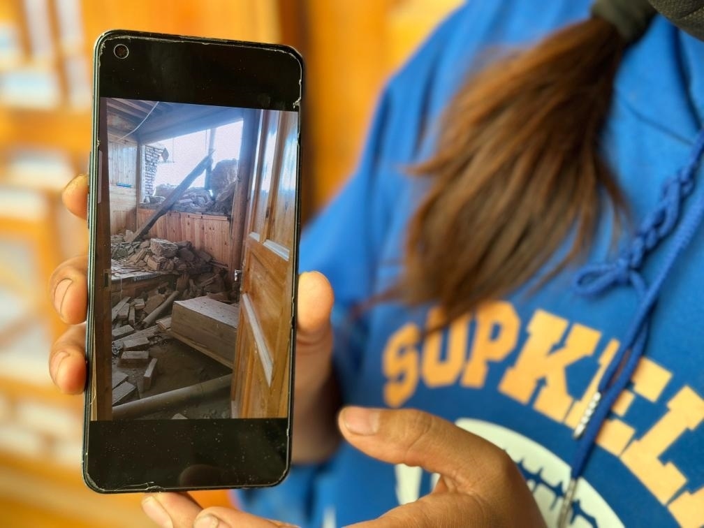 圖為7月17日拉毛東智在手機(jī)上找出地震后房屋受損的照片。新華社記者 張子琪 攝