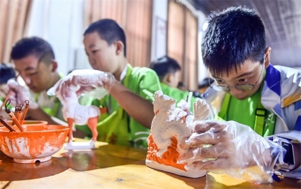 小朋友們?cè)诼尻柺忻辖騾^(qū)朝陽鎮(zhèn)南石山村體驗(yàn)唐三彩素胎施釉技藝。圖片來源：視覺中國