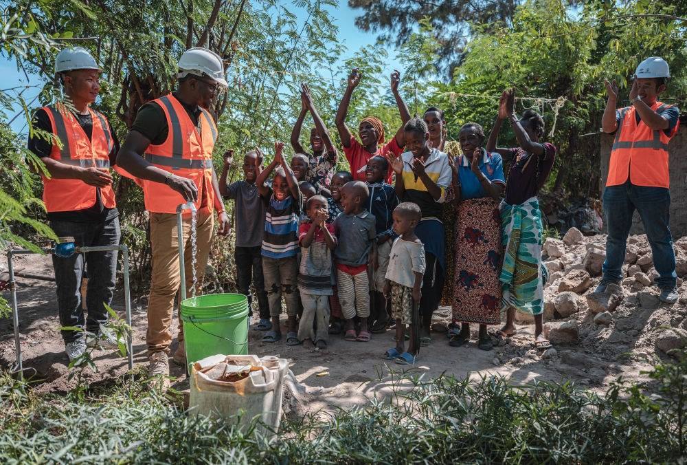 2023年6月13日，在坦桑尼亞姆萬扎省米松圭，工作人員接通水管后贏得當(dāng)?shù)鼐用窆恼茪g呼。新華社記者 王冠森 攝