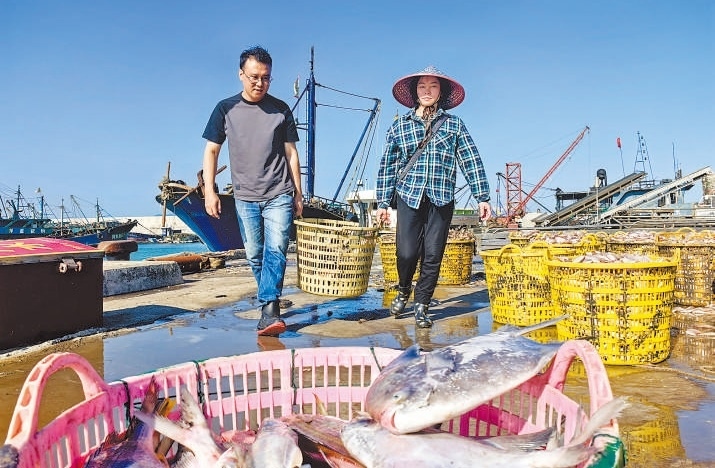 許小斌（左）和漁民一起搬運海鮮。本報記者 付 文攝