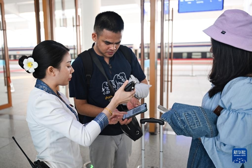 10月12日，在老撾萬象中老鐵路萬象站，工作人員檢驗(yàn)乘客車票。新華社記者 程一恒 攝