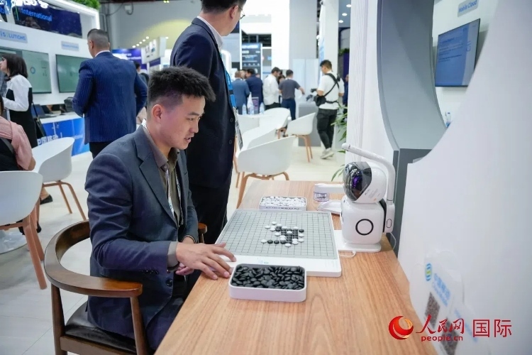 觀眾在中國移動國際有限公司展臺體驗(yàn)智慧圍棋機(jī)器人。人民網(wǎng) 塔里克·易卜拉欣攝