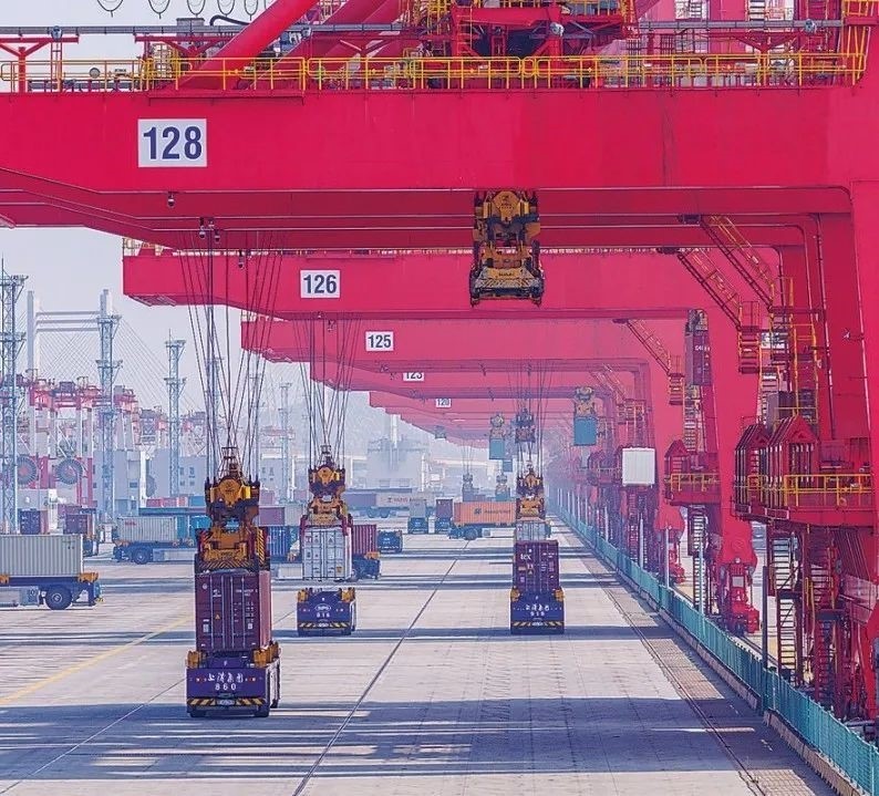 共建“一帶一路”國家在工作制度對(duì)接、技術(shù)標(biāo)準(zhǔn)協(xié)調(diào)、檢驗(yàn)結(jié)果互認(rèn)等方面強(qiáng)化合作、統(tǒng)一標(biāo)準(zhǔn)，貿(mào)易自由化便利化水平不斷提升。上海洋山港海關(guān)對(duì)接共建國家進(jìn)出口貨物相關(guān)標(biāo)準(zhǔn)，推動(dòng)通關(guān)一體化方式申報(bào)，提升通關(guān)效率。圖為無人駕駛的全自動(dòng)導(dǎo)引車在洋山港穿梭往來，搬運(yùn)集裝箱。王初 攝