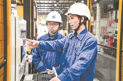 在廣西柳工機械股份有限公司生產(chǎn)車間內(nèi)，一名高級技師（右）給徒弟講解數(shù)控設(shè)備操作細節(jié)。新華社記者 曹祎銘攝
