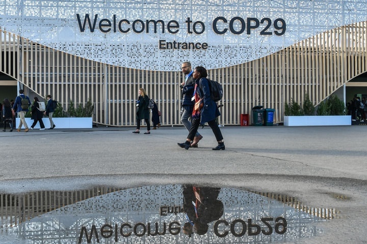 2024年11月15日，在阿塞拜疆首都巴庫，人們經(jīng)過聯(lián)合國氣候變化巴庫大會(huì)的會(huì)場(chǎng)。新華社記者 曹陽 攝