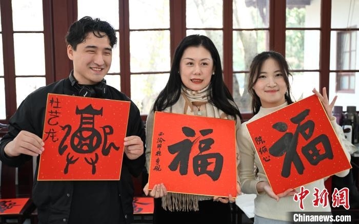 1月20日，外籍留學生和西泠印社社員李硯(中)展示各自創(chuàng)作的福貼。當日，來自巴西、馬來西亞、加納、哈薩克斯坦的外籍留學生在浙江杭州西泠印社體驗福貼、春聯(lián)和篆刻，感受古老的中國傳統(tǒng)文化。中新社記者 王剛 攝