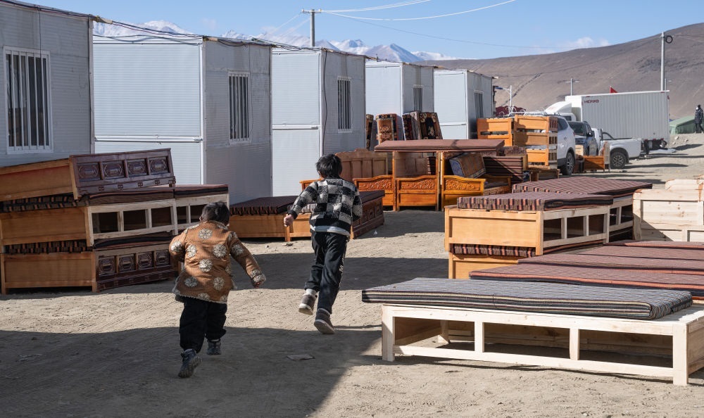 2025年1月13日，在定日縣嘎旦村，兩個(gè)孩子在剛運(yùn)來的兩排藏床間奔跑。新華社記者丁增尼達(dá) 攝