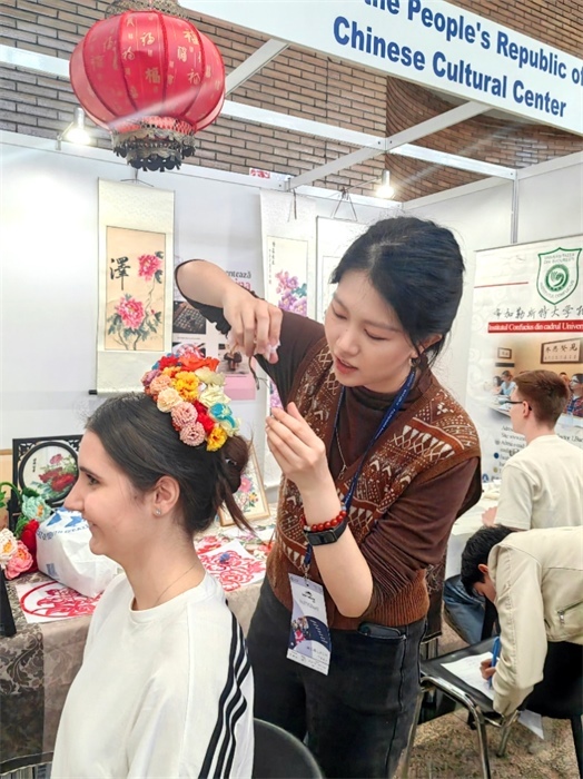 展覽正值羅馬尼亞迎春花節(jié)，國際中文教師志愿者潘婧穎向游客們介紹了國家非物質(zhì)文化遺產(chǎn)——福建泉州的簪花文化。布加勒斯特大學(xué)孔子學(xué)院供圖。