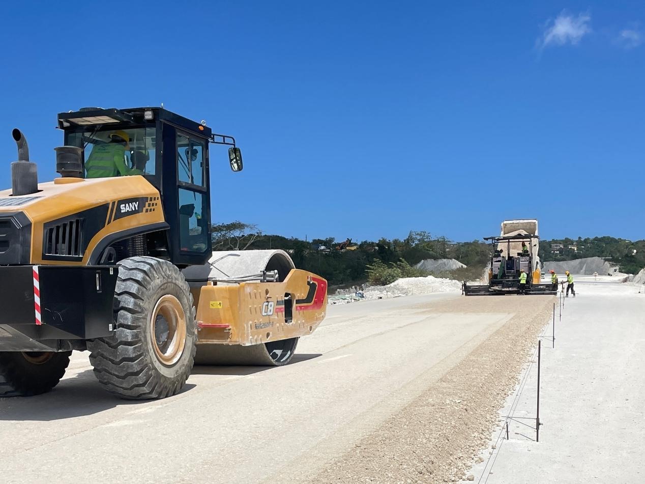 圖為中企承建的牙買加蒙特哥貝繞城路項(xiàng)目基層試驗(yàn)段正在進(jìn)行攤鋪和碾壓施工，相關(guān)施工工作已于日前順利完成。中國港灣美洲區(qū)域公司供圖
