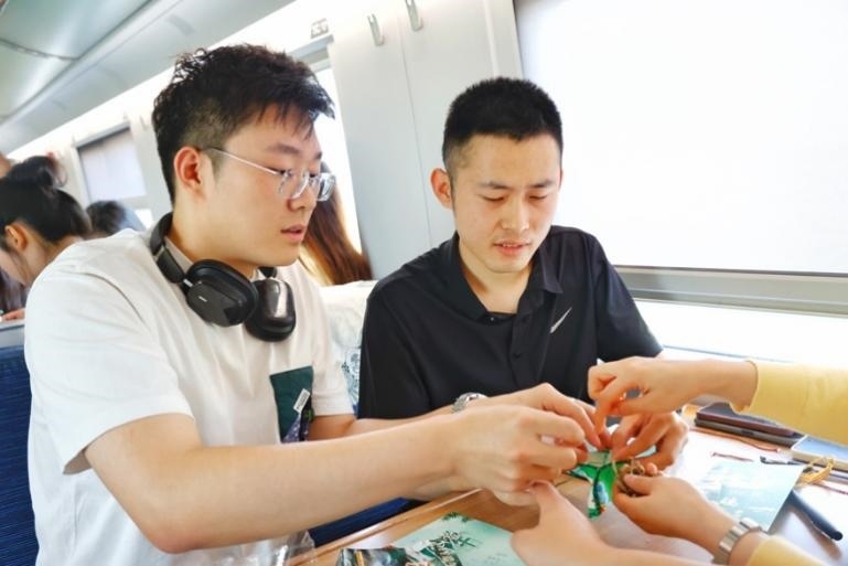 G232次旅客親手制作端午荷包和五彩繩。王磊攝