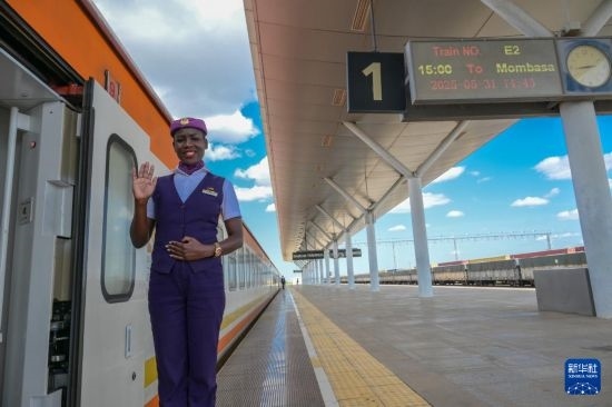 5月31日，在蒙內(nèi)鐵路內(nèi)羅畢站，一名乘務(wù)員在即將開往蒙巴薩的E2次列車旁等候乘客。新華社記者 楊光 攝