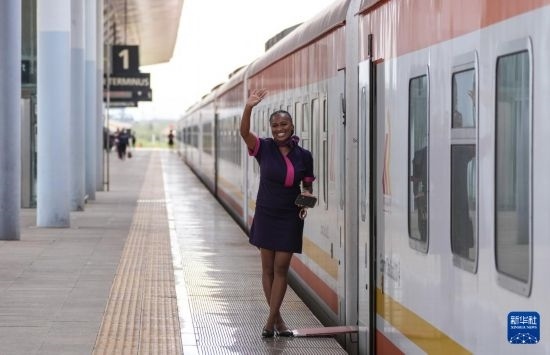 5月31日，在蒙內(nèi)鐵路內(nèi)羅畢站，一名乘務(wù)員在即將開往蒙巴薩的E2次列車旁等候乘客。新華社記者 李亞輝 攝